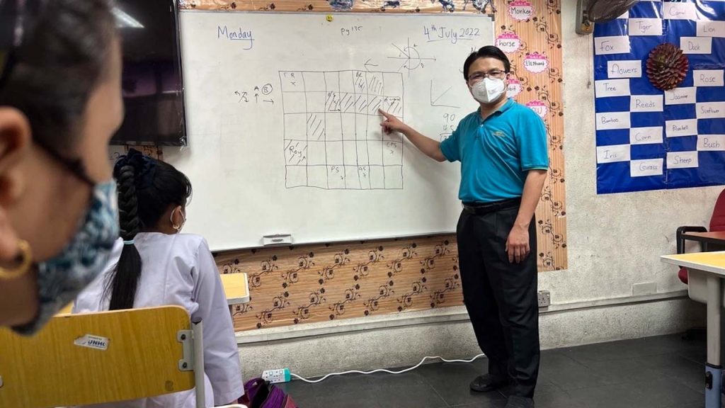 A teacher in from of class teaching refugees